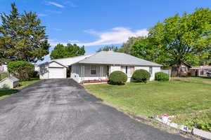 Ranch-style house featuring a garage and a front lawn