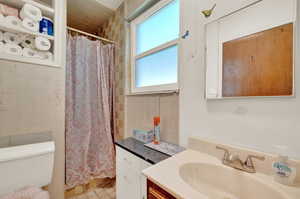 Bathroom with vanity, toilet, and a shower with shower curtain