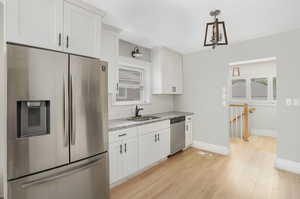 Kitchen with light hardwood / wood-style flooring, stainless steel appliances, sink, and white cabinetry