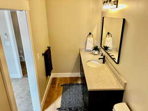 Bathroom featuring vanity, baseboards, toilet, and wood finished floors