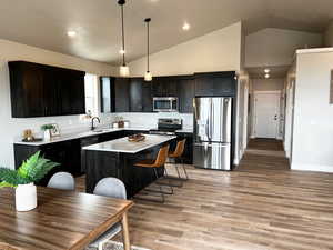 Kitchen featuring appliances with stainless steel finishes, light wood finished floors, a sink, and lofted ceiling