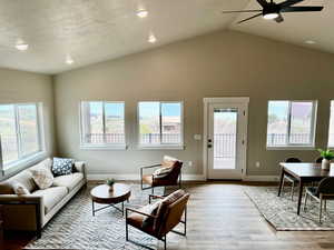 Living room with baseboards, ceiling fan, recessed lighting, light wood-style flooring, and vaulted ceiling