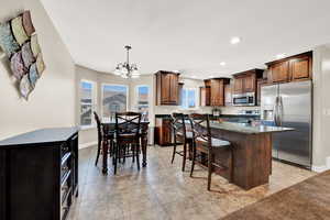 Kitchen featuring a chandelier, a kitchen breakfast bar, a kitchen island, hanging light fixtures, and appliances with stainless steel finishes