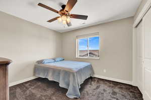 Carpeted bedroom featuring ceiling fan and a closet