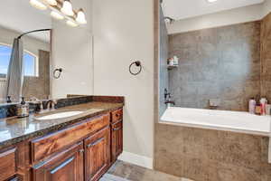 Bathroom featuring tiled shower / bath combo, vanity, and tile patterned flooring