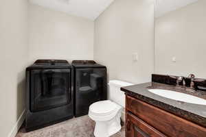 Bathroom with vanity, toilet, washing machine and dryer, and tile patterned flooring