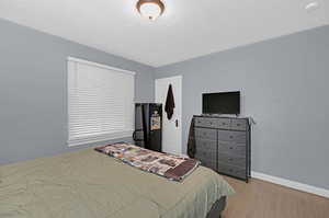 Bedroom with light wood-type flooring and a textured ceiling