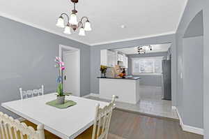 Dining room featuring crown molding, a textured ceiling, light hardwood / wood-style flooring, an inviting chandelier, and sink