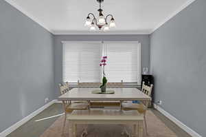 Dining area with dark hardwood / wood-style floors, a notable chandelier, and ornamental molding