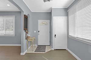 Foyer with crown molding and light hardwood / wood-style flooring