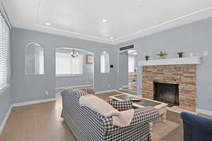 Living room featuring hardwood / wood-style floors, a notable chandelier, and a stone fireplace