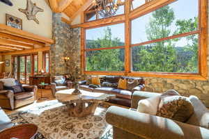 Living room with hardwood / wood-style floors, high vaulted ceiling, a fireplace, and beam ceiling