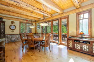 Dining area featuring a wealth of natural light, light hardwood / wood-style flooring, beamed ceiling, and wooden ceiling