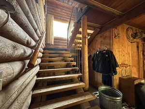 Stairs featuring wood ceiling and log walls