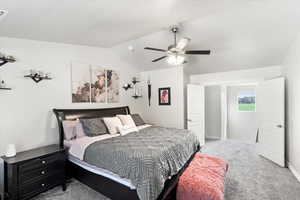 Bedroom with vaulted ceiling, ceiling fan, and carpet floors