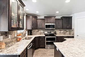 Kitchen with light wood-type flooring, sink, appliances with stainless steel finishes, and decorative backsplash