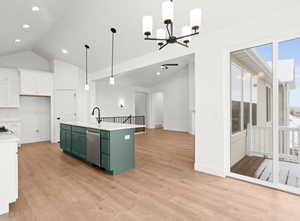 Kitchen with light wood-type flooring, stainless steel dishwasher, vaulted ceiling, decorative light fixtures, and a center island with sink