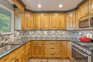 Kitchen featuring appliances with stainless steel finishes, dark stone countertops, tasteful backsplash, and sink