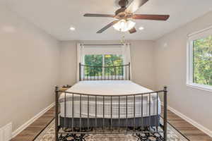 Bedroom with multiple windows, ceiling fan, and wood-type flooring