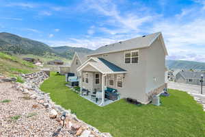 Back of property with a mountain view, a patio, cooling unit, a lawn, and an outdoor living space