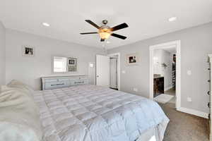 Carpeted bedroom featuring ceiling fan and ensuite bathroom