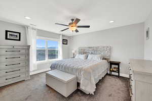 Carpeted bedroom featuring ceiling fan