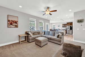 Carpeted living room with ceiling fan and sink