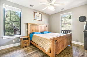 Bedroom with multiple windows and dark hardwood / wood-style floors