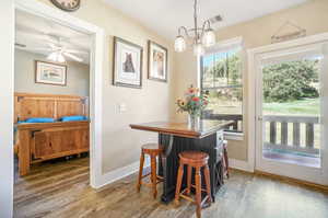 Dining room featuring a healthy amount of sunlight, ceiling fan with notable chandelier, and hardwood / wood-style floors