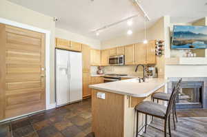 Kitchen with a tiled fireplace, appliances with stainless steel finishes, sink, kitchen peninsula, and a kitchen breakfast bar