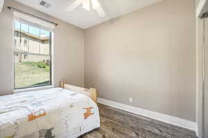 Bedroom featuring dark wood-type flooring, multiple windows, and ceiling fan