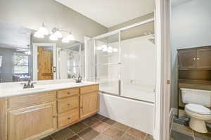 Full bathroom featuring ceiling fan, toilet, combined bath / shower with glass door, and vanity