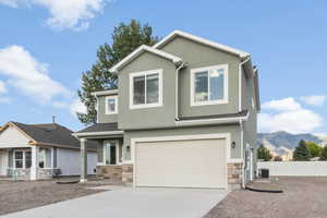 View of front facade with a mountain view, central air condition unit, and a garage