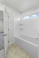 Bathroom featuring bathing tub / shower combination and tile patterned flooring