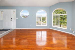 Entryway with vaulted ceiling, hardwood / wood-style floors, and a healthy amount of sunlight