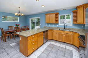 Kitchen featuring dishwasher, sink, a notable chandelier, kitchen peninsula, and black stove