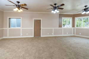 Carpeted family room with a textured ceiling, crown molding, and ceiling fan