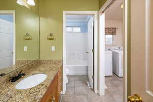 Bathroom featuring tile patterned flooring, independent washer and dryer, ornamental molding, vanity, and toilet