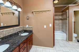 Full bathroom with vanity, tile patterned flooring, ornamental molding, toilet, and tiled shower / bath