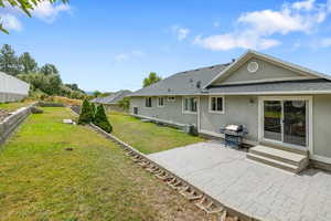 Rear view of property featuring a lawn and a patio