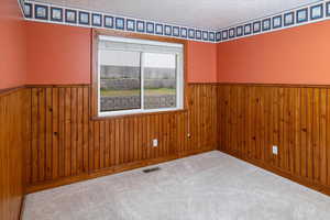 Bedroom #3 featuring wood walls, a textured ceiling, and carpet flooring