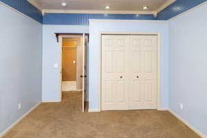 Bedroom #4 with crown molding, light colored carpet, and a closet