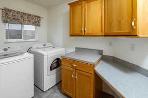 Laundry room featuring washing machine and clothes dryer, cabinets, and light tile patterned floors