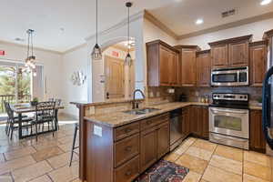 Kitchen featuring appliances with stainless steel finishes, a notable chandelier, sink, kitchen peninsula, and a kitchen bar