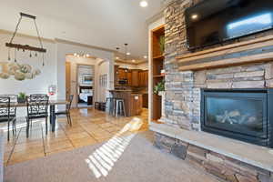 Tiled living room featuring ornamental molding and a stone fireplace