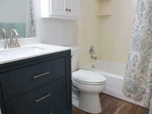 Family Full bathroom with vanity, toilet, hardwood / wood-style floors, and shower / bath combo with shower curtain