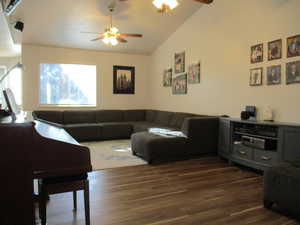 Living room featuring ceiling fan, dark hardwood / wood-style floors, and vaulted ceiling