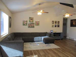 Living room featuring lofted ceiling, ceiling fan, and dark hardwood / wood-style floors