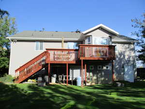 Back of house featuring a lawn and a deck