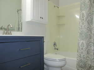 family Full bathroom featuring shower / bath combo with shower curtain, toilet, and vanity